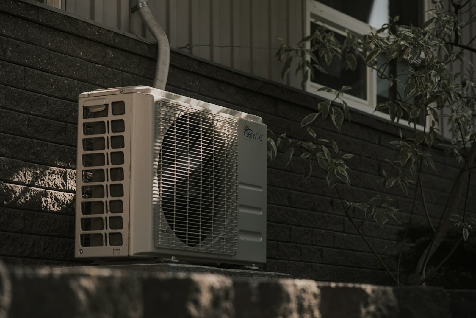Outdoor air conditioning unit beside a brick wall