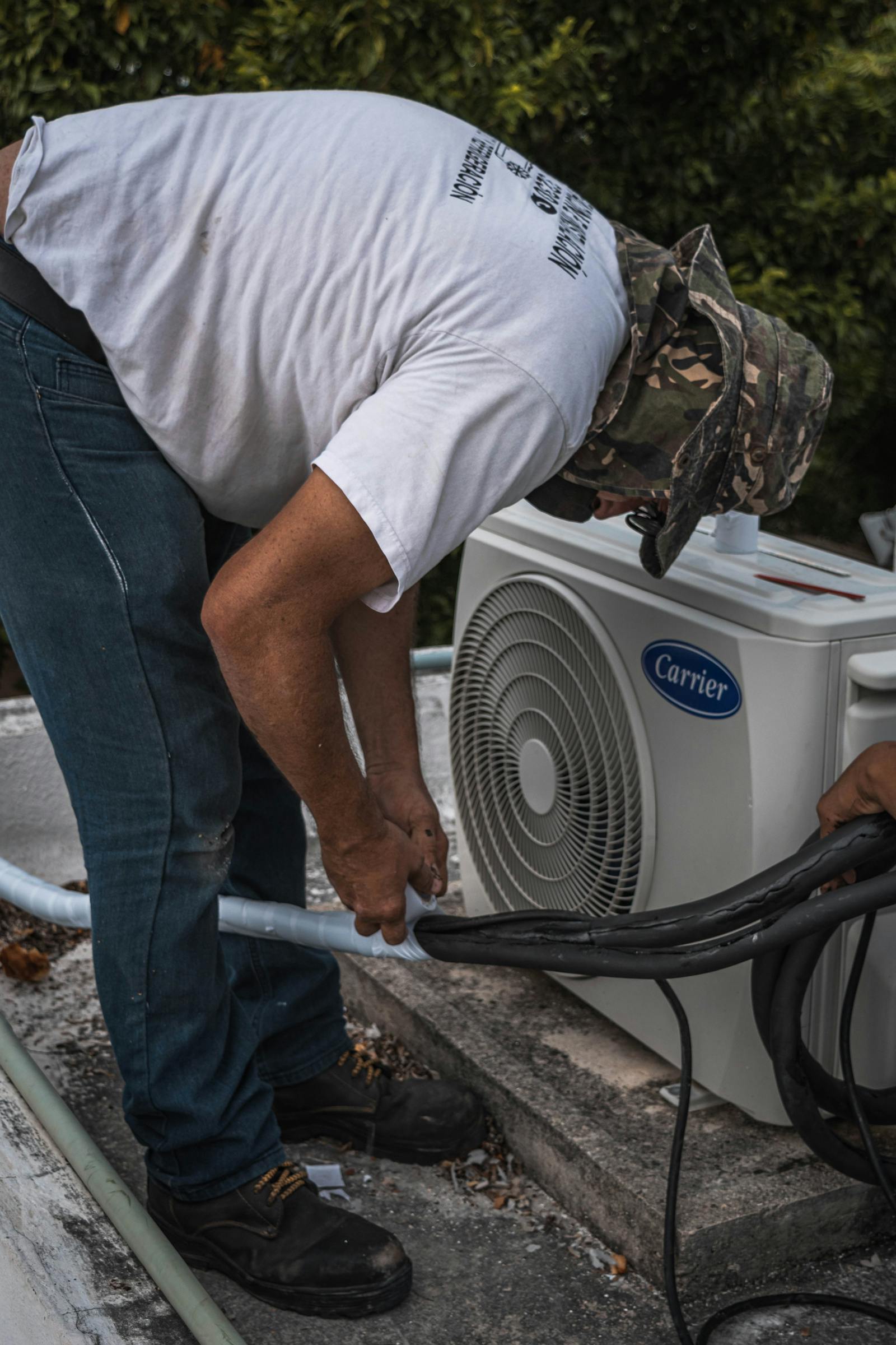 HVAC technician working on hose connections at a residential air conditioning unit