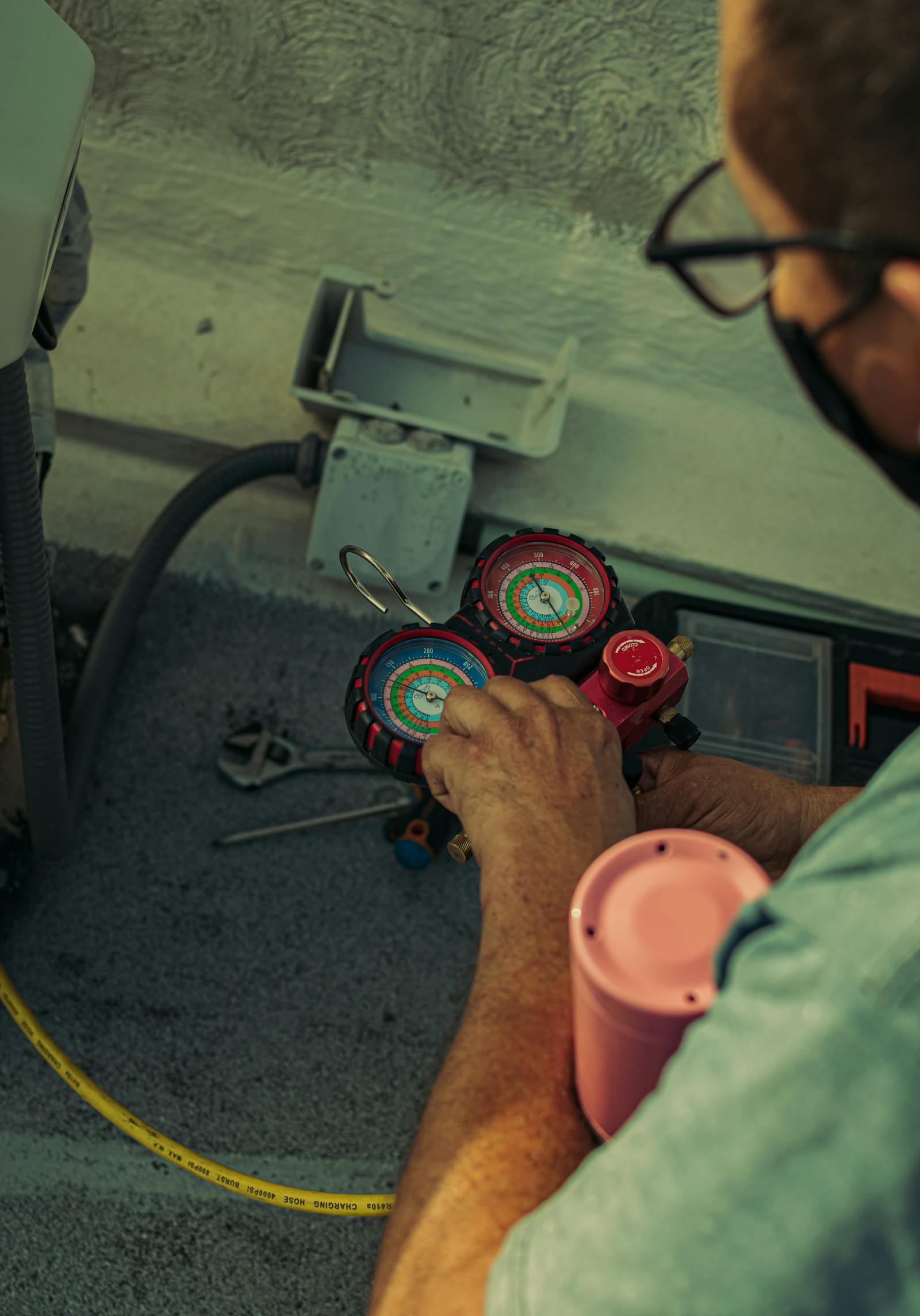 HVAC technician adjusting a refrigerant manifold gauge during AC service